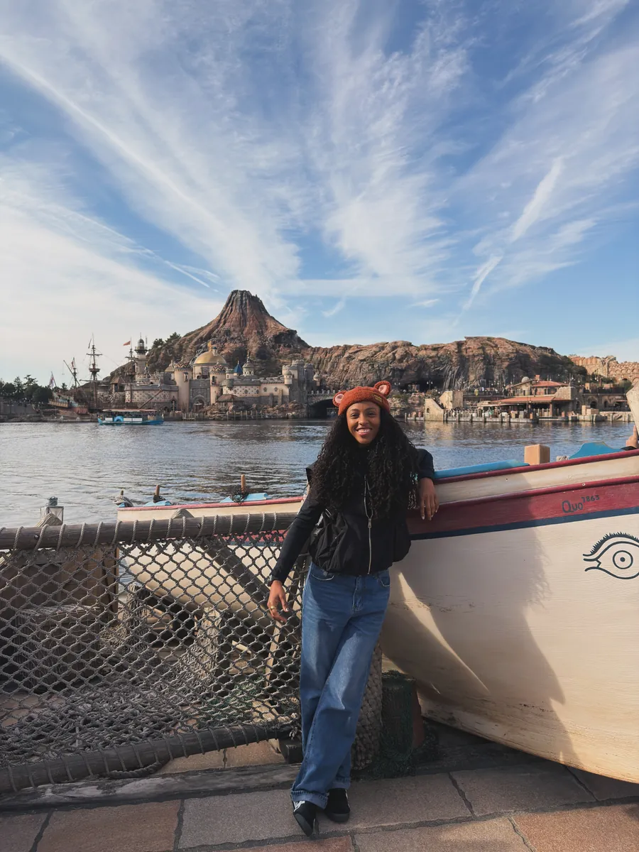 Kay leaning on a boat in front of a volcano-shaped mountain at Tokyo DisneySea